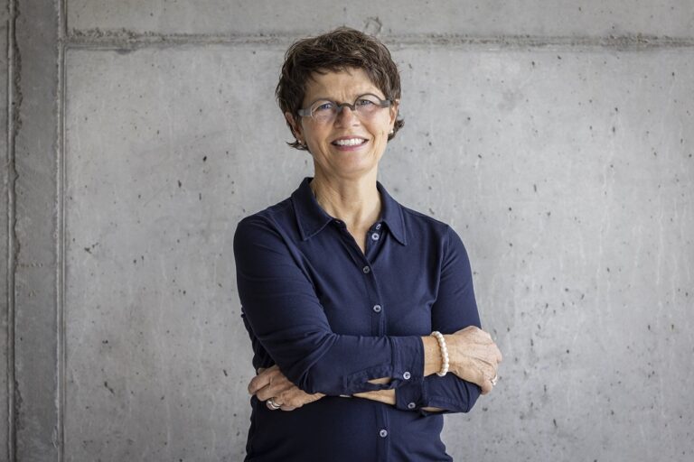 Ein Foto von der Frau Isabelle Lehmann, Campusbetrieb und Empfang, vor einer grauen Wand.