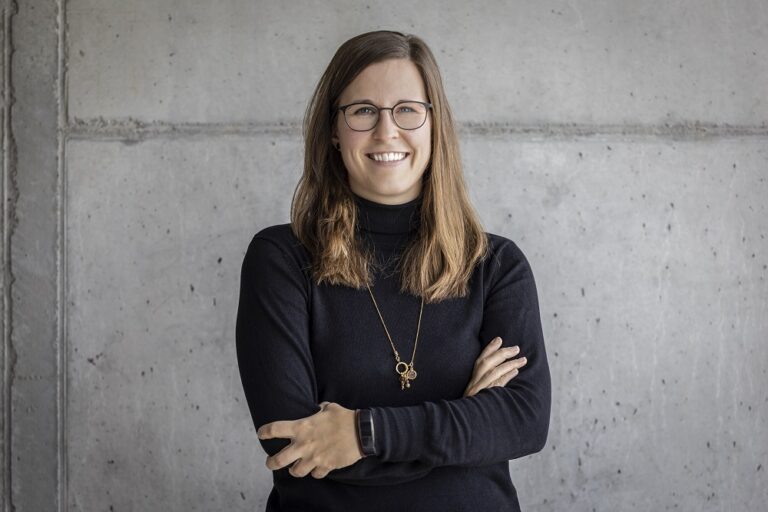 Ein Foto von der Frau Anissa Kuster, Networking Center und Marketing & Kommunikation, vor einer grauen Wand.