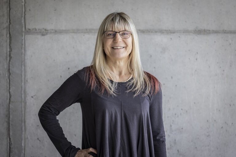 Ein Foto von der Frau Bärbel Selm, Leiterin Networking Center, vor einer grauen Wand.