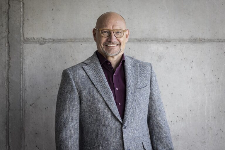 Ein Foto von dem Mann Hans Ebinger, Geschäftsführer von dem Switzerland Innovation Park Ost, vor einer grauen Wand.