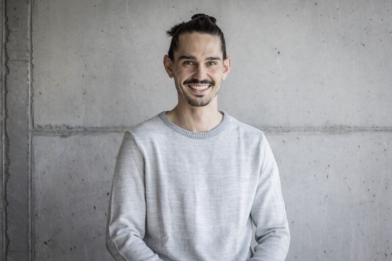 Ein Foto von dem Mann Michael Deuber, Campusbetrieb und Empfang, vor einer grauen Wand.