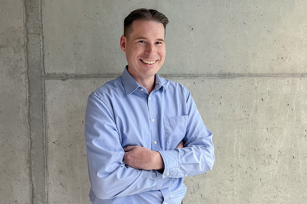 Ein Foto von dem Mann Sven Hoffmann, der der Leiter von dem R&D Center ist, vor einem grauen Wand.